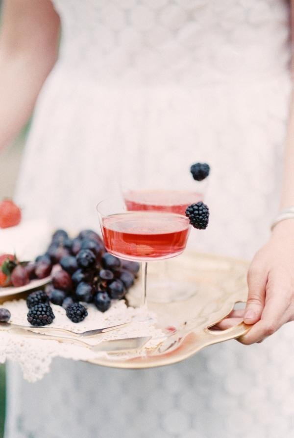 Duas taças de berry bubbles, uma bebida vermelha com bastante borbulhas, decorada com um amoras na borda. 