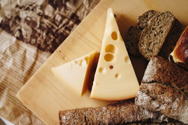 Tábua de madeira com queijos e pães. 