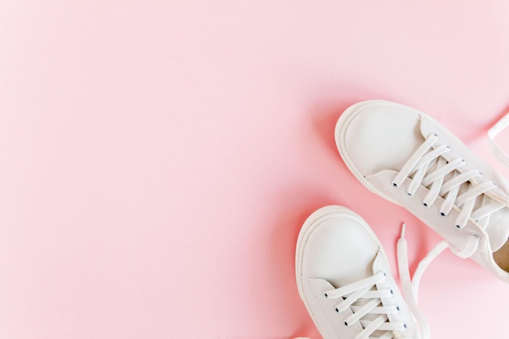 Um par de calçados brancos, em um fundo rosa.