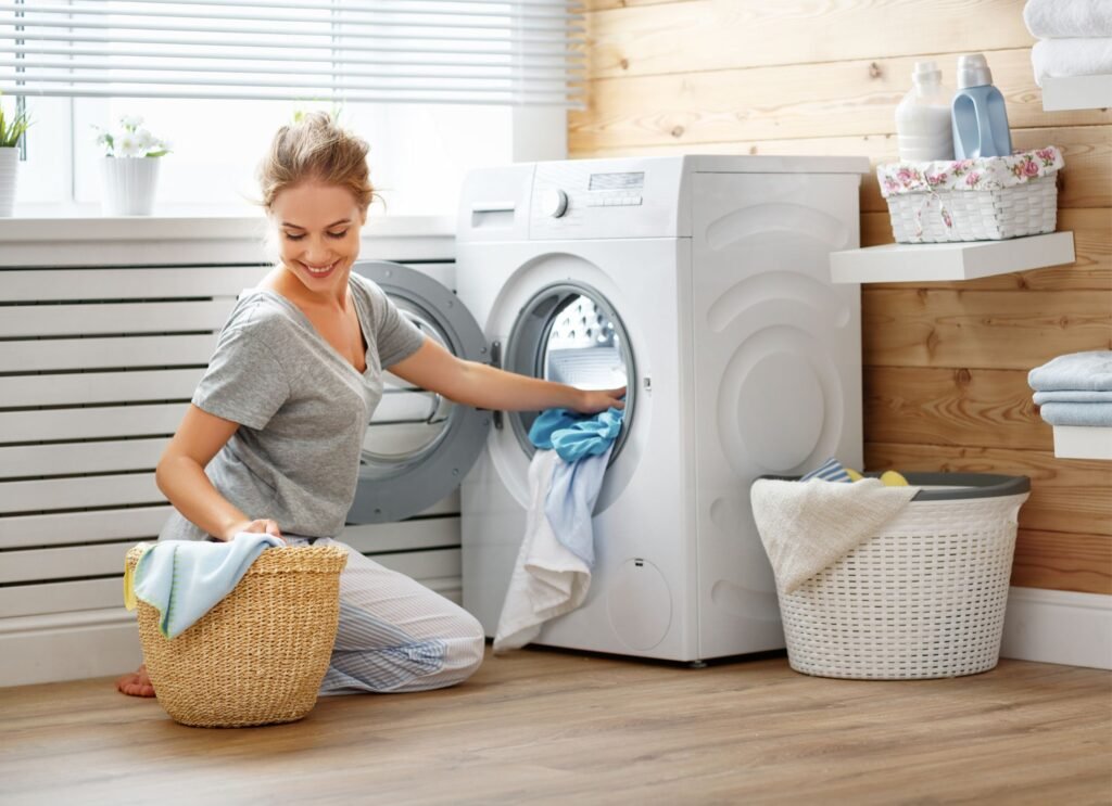 Mulher colocando suas roupas na máquina de lavar.