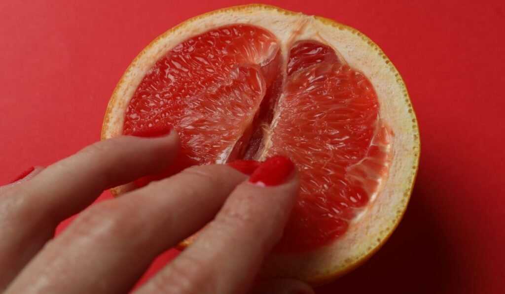 Mulher tocando uma laranja com os dedos