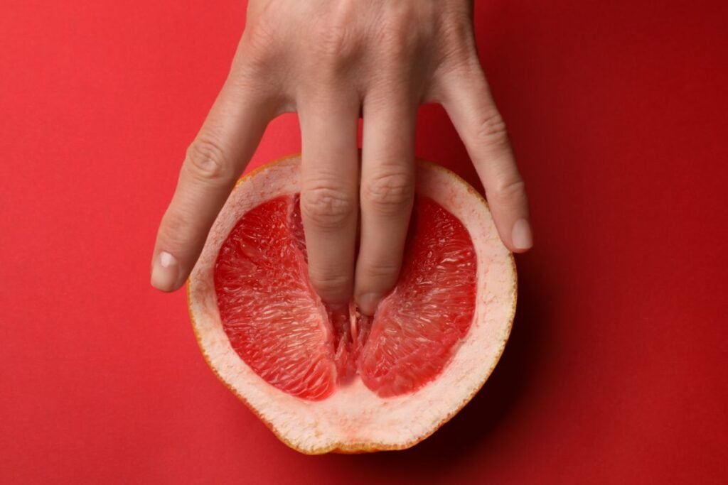 Dedos dentro de uma laranja cortada ao meio