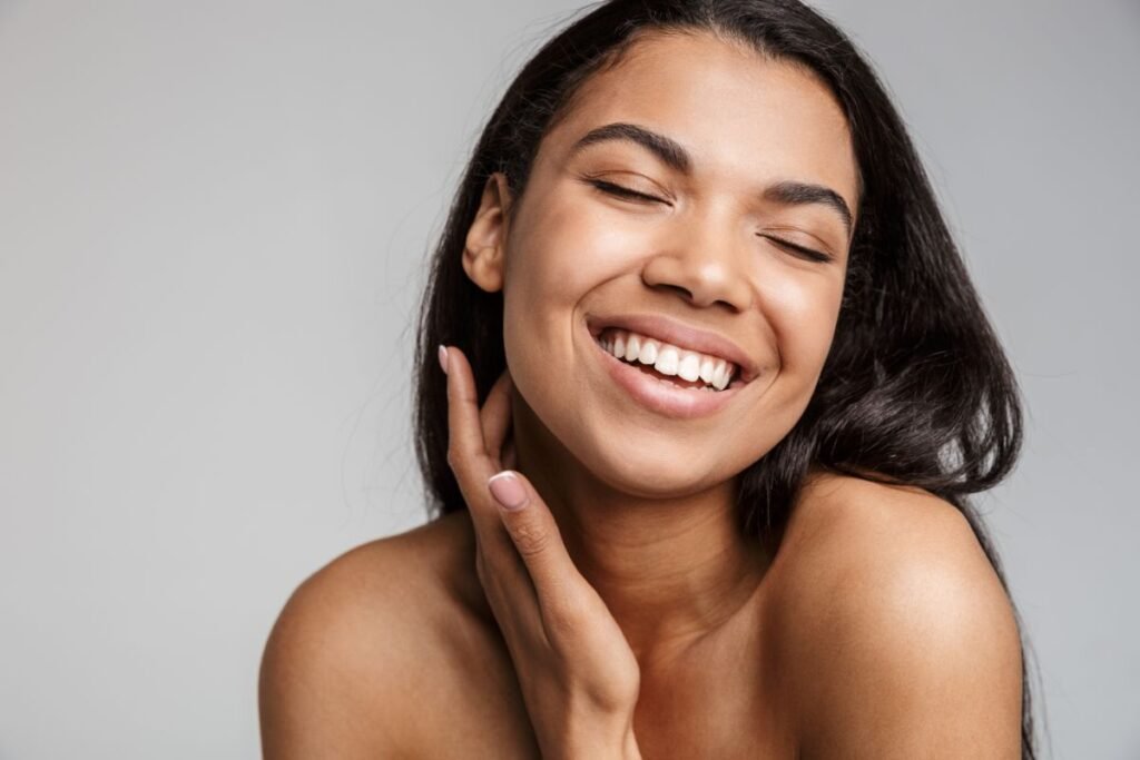 Mulher sorrindo passando a mão no rosto