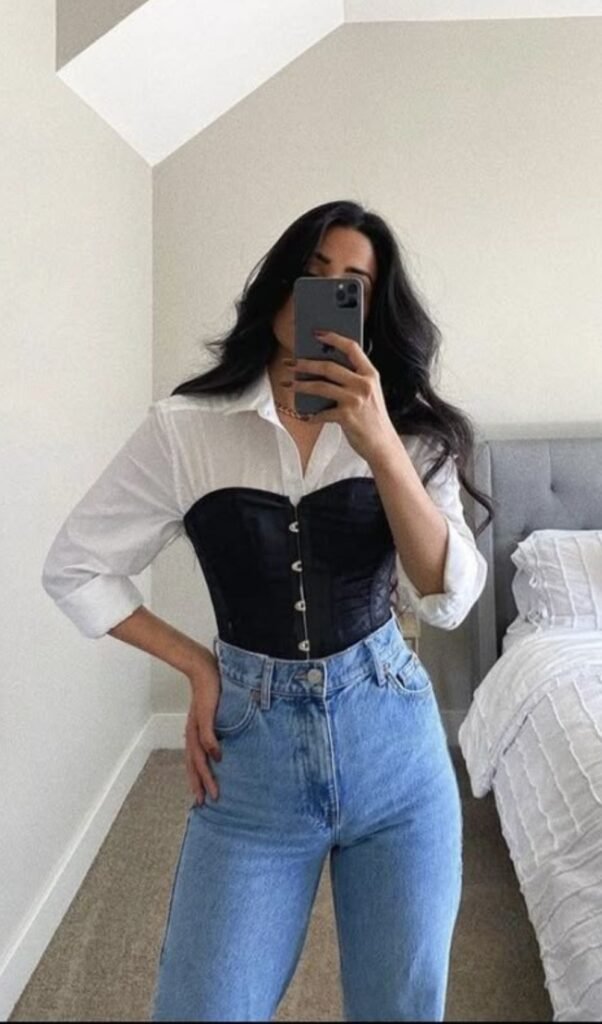 Mulher usando espartilho preto com camisa branca por baixo e calça jeans azul