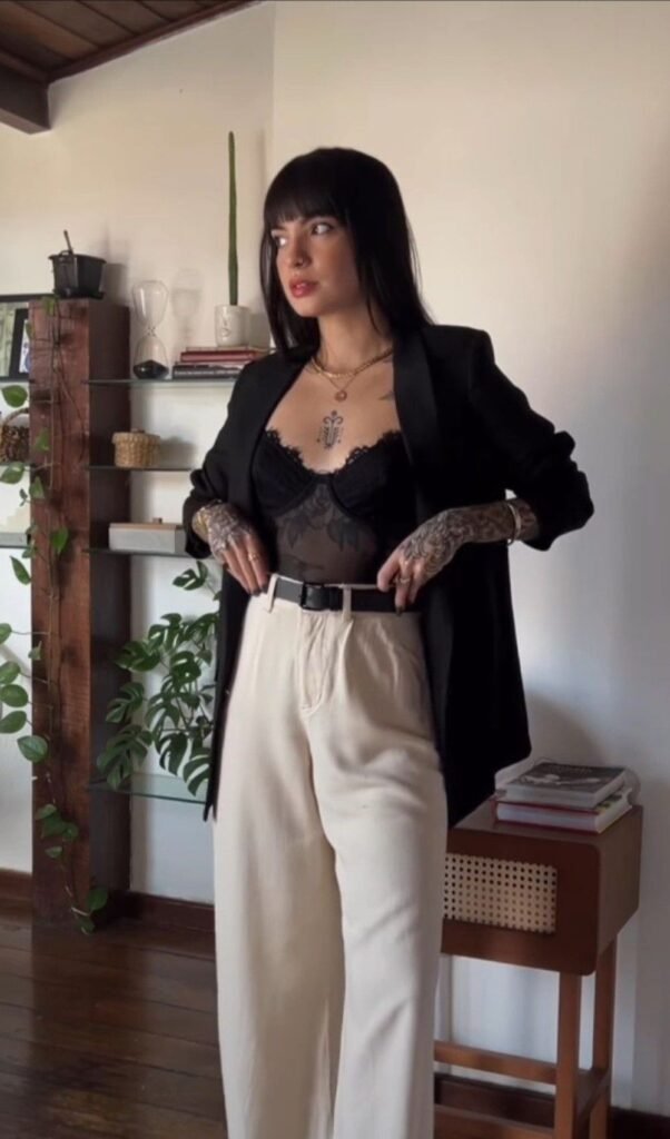 Mulher usando espartilho de renda com blazer preto e calça de alfaiataria off-white